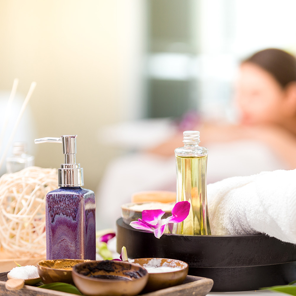 Spa Treatments With Orchid Flowers On Table Background Of Young Woman Relaxing Spa